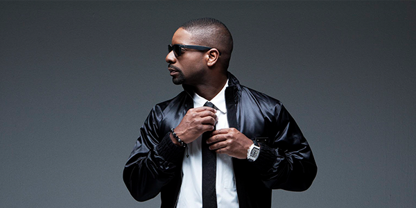 DJ Irie with a suit on adjusting tie